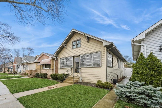 bungalow with central AC unit and a front yard