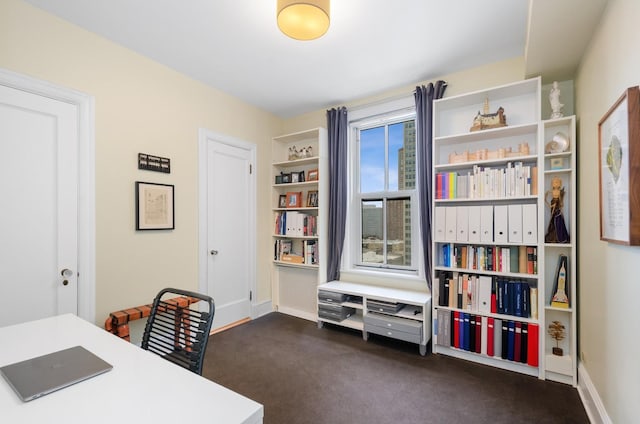 home office with dark carpet and baseboards