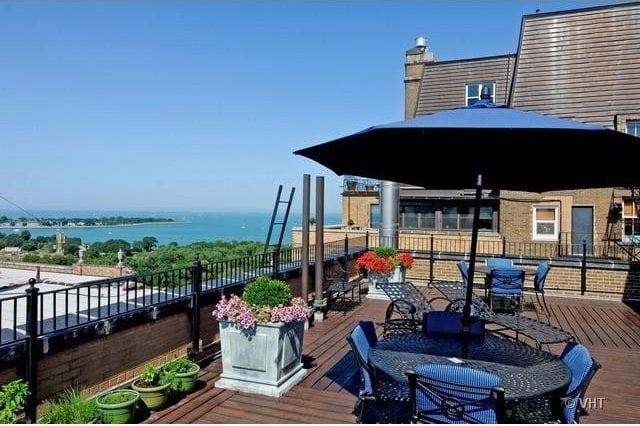 deck with outdoor dining area and a water view