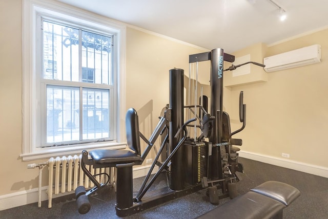 workout room featuring a wall unit AC, crown molding, radiator, track lighting, and baseboards