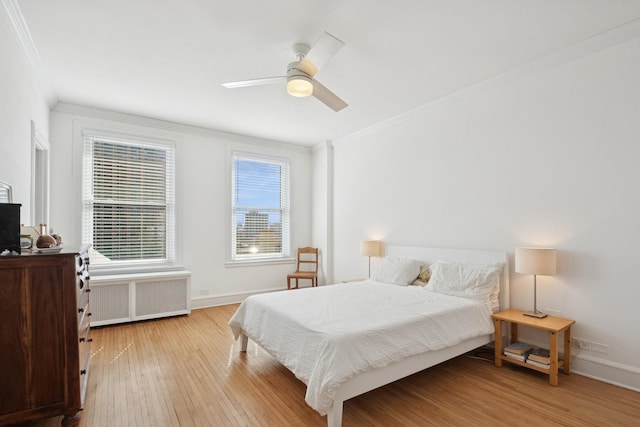 bedroom featuring ornamental molding, radiator, light wood-style flooring, and baseboards