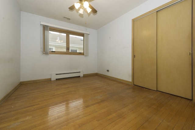 unfurnished bedroom with baseboards, baseboard heating, visible vents, and light wood-style floors