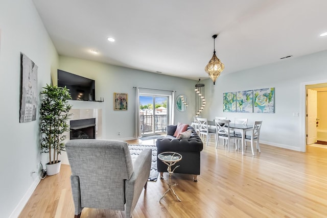 living room with baseboards, light wood finished floors, recessed lighting, a fireplace, and stairs