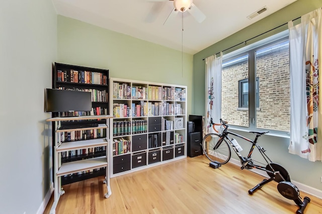 exercise area with visible vents, ceiling fan, baseboards, and wood finished floors