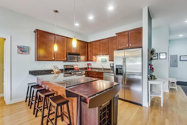 kitchen featuring a peninsula, light wood-style floors, appliances with stainless steel finishes, and a sink