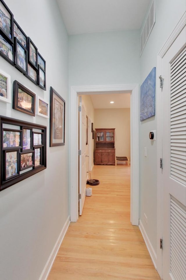 corridor with visible vents, baseboards, and light wood-style floors