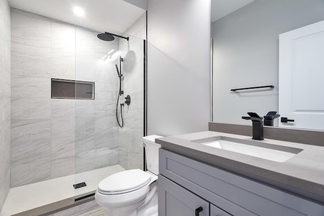 full bath with tiled shower, vanity, and toilet