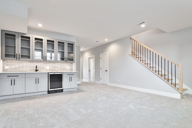 kitchen with wine cooler, tasteful backsplash, recessed lighting, light colored carpet, and gray cabinetry