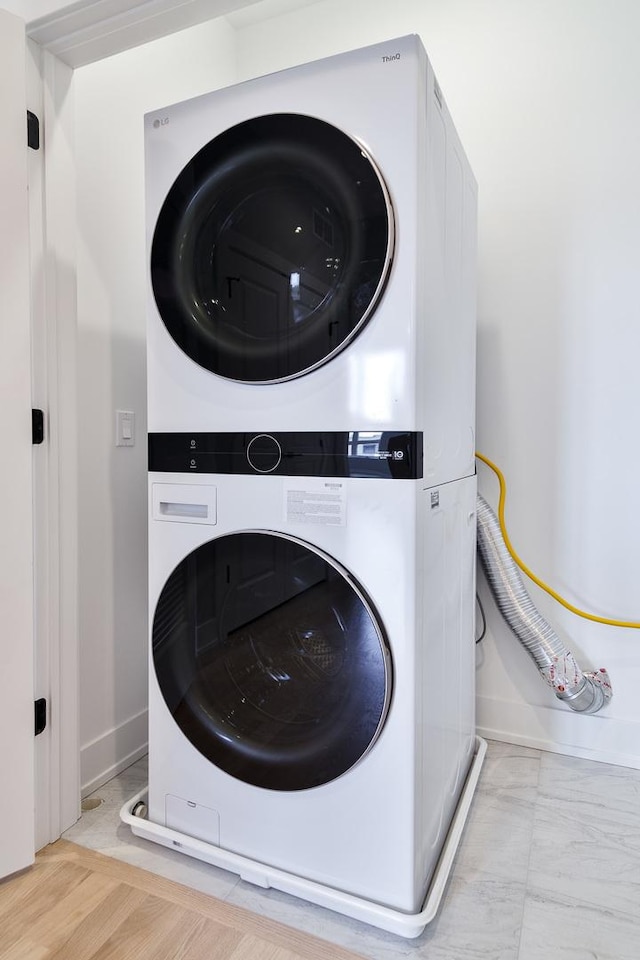 washroom with laundry area, stacked washer / dryer, and baseboards