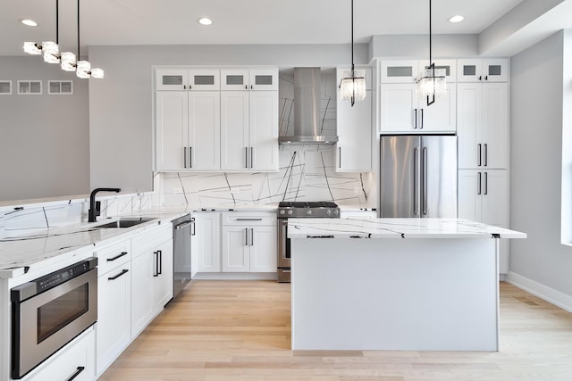 kitchen with stainless steel appliances, decorative backsplash, a sink, wall chimney range hood, and a kitchen island