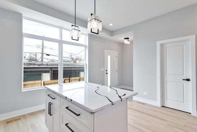 kitchen featuring white cabinetry, baseboards, visible vents, and pendant lighting