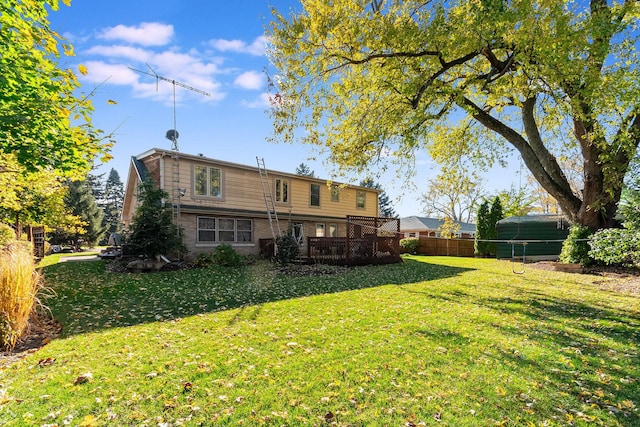 rear view of property featuring a yard, brick siding, fence, and a wooden deck