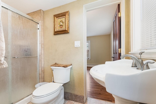 bathroom featuring a stall shower, plenty of natural light, toilet, and a baseboard radiator