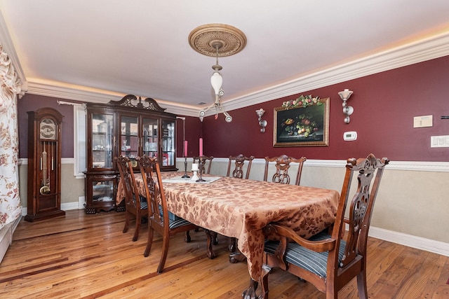 dining space with light wood-style floors, crown molding, and baseboards