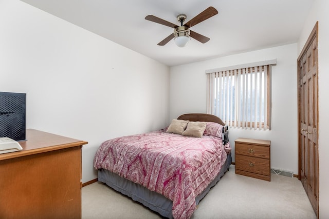 bedroom with a closet, light colored carpet, visible vents, ceiling fan, and baseboards