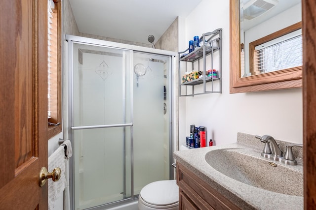 bathroom with visible vents, a shower stall, toilet, and vanity