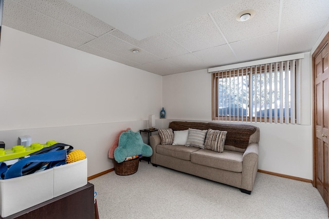 living room featuring carpet, a paneled ceiling, and baseboards