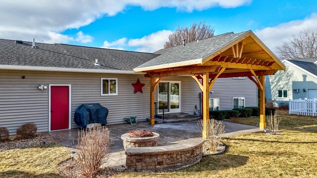 rear view of house featuring a shingled roof, an outdoor fire pit, a patio area, and a yard