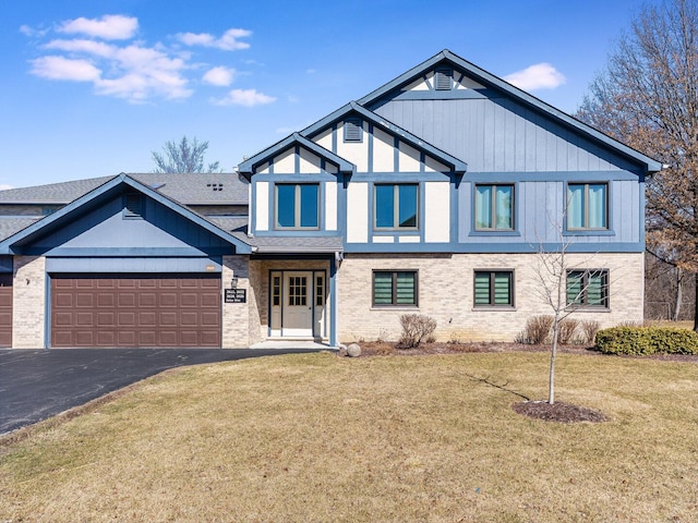 view of front facade with brick siding, aphalt driveway, a garage, and a front lawn