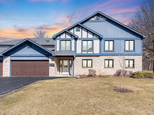 view of front of property featuring aphalt driveway, a lawn, and a garage