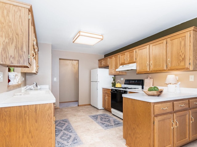 kitchen with freestanding refrigerator, a sink, light countertops, under cabinet range hood, and gas range