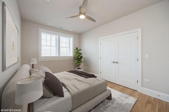 bedroom featuring baseboards, a ceiling fan, visible vents, and light wood-style floors