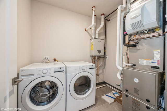 clothes washing area featuring laundry area, baseboards, water heater, separate washer and dryer, and light tile patterned flooring