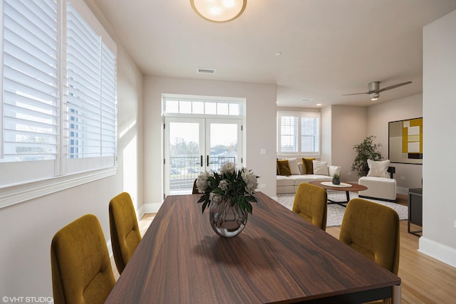 dining area with a ceiling fan, baseboards, visible vents, light wood-style floors, and french doors