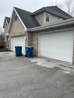 view of home's exterior with aphalt driveway, an attached garage, and brick siding