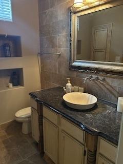 bathroom with backsplash, toilet, and vanity