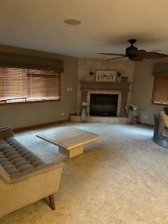 carpeted living room with a ceiling fan and a fireplace