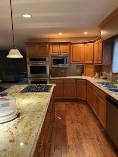 kitchen featuring tasteful backsplash, appliances with stainless steel finishes, wood finished floors, and brown cabinetry