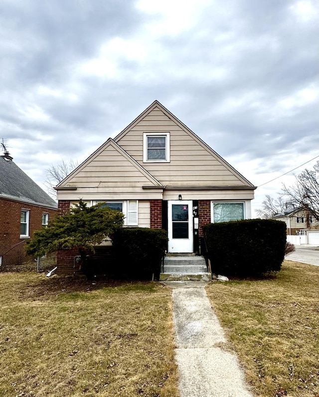 bungalow-style house with entry steps, brick siding, and a front yard