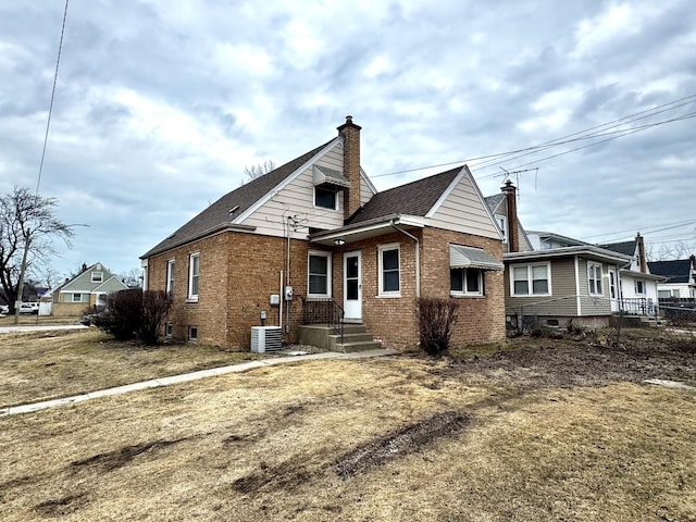 back of property with brick siding, a chimney, cooling unit, and fence