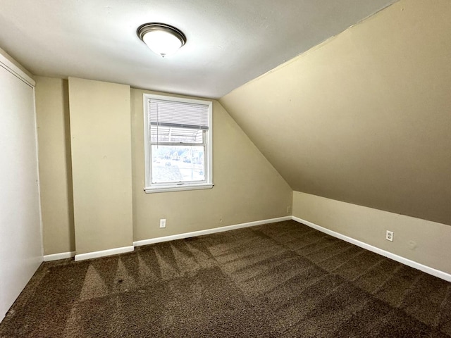 additional living space featuring baseboards, vaulted ceiling, and carpet flooring