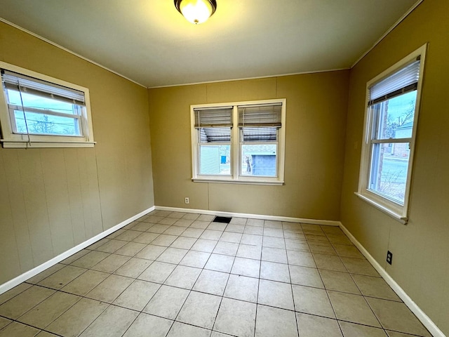 empty room with a wealth of natural light, visible vents, baseboards, and light tile patterned flooring