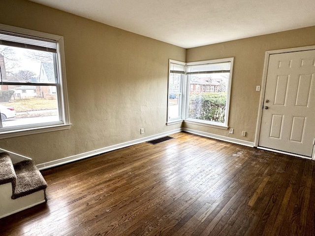 foyer featuring a wealth of natural light, wood-type flooring, visible vents, and baseboards