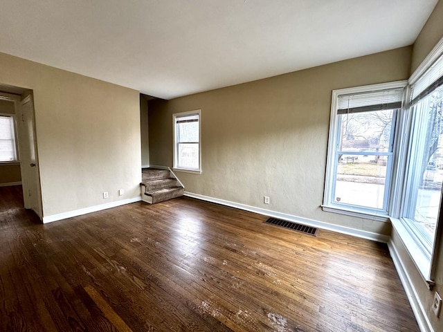 unfurnished living room featuring stairs, dark wood-style floors, visible vents, and baseboards