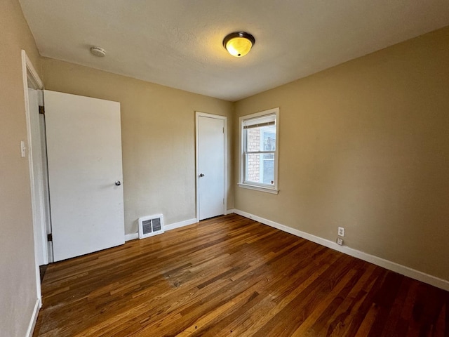 unfurnished bedroom featuring a closet, wood finished floors, visible vents, and baseboards