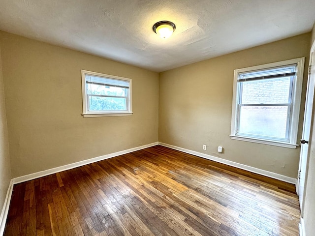 spare room with a textured ceiling, baseboards, and hardwood / wood-style flooring