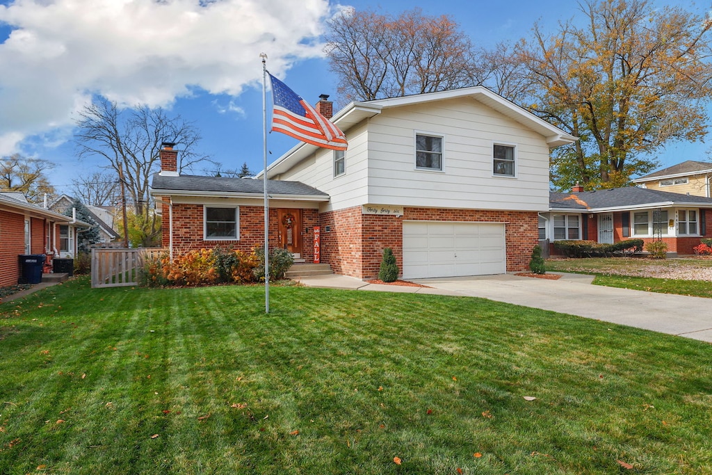 tri-level home featuring a front yard, a chimney, concrete driveway, and brick siding