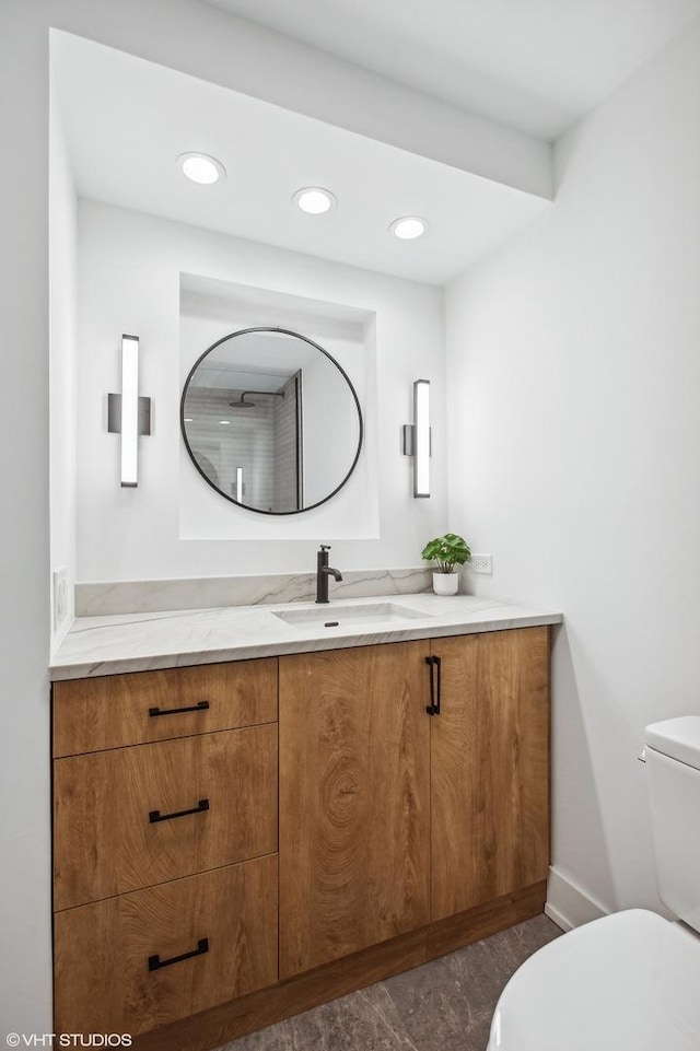 bathroom featuring baseboards, vanity, toilet, and recessed lighting