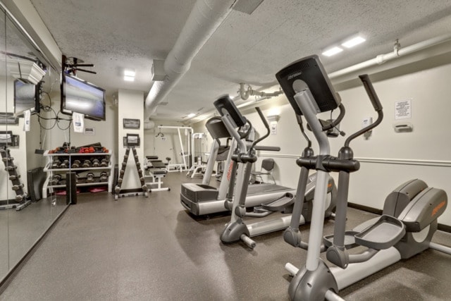 gym with a textured ceiling and baseboards