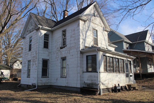 view of side of property featuring a chimney and a sunroom