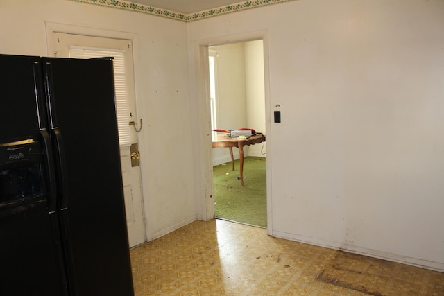 kitchen featuring light floors and black fridge