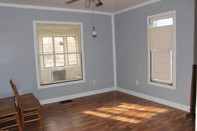 spare room featuring dark wood-style floors, plenty of natural light, a ceiling fan, and visible vents