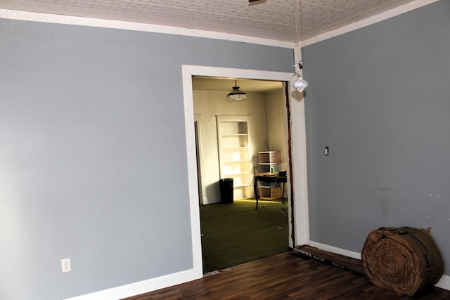 spare room featuring built in shelves, baseboards, and wood finished floors