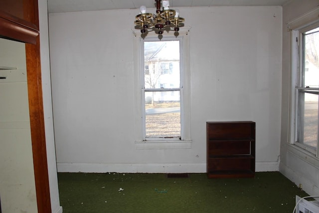 spare room with a chandelier, a healthy amount of sunlight, and baseboards