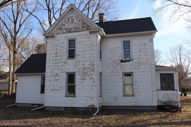 back of property featuring a chimney and a shingled roof