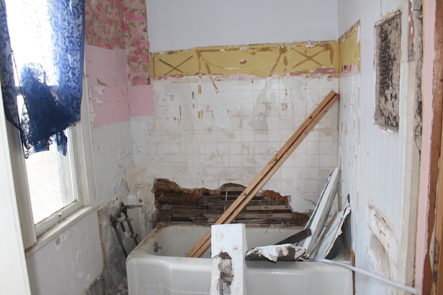 full bath featuring a bath and tile walls